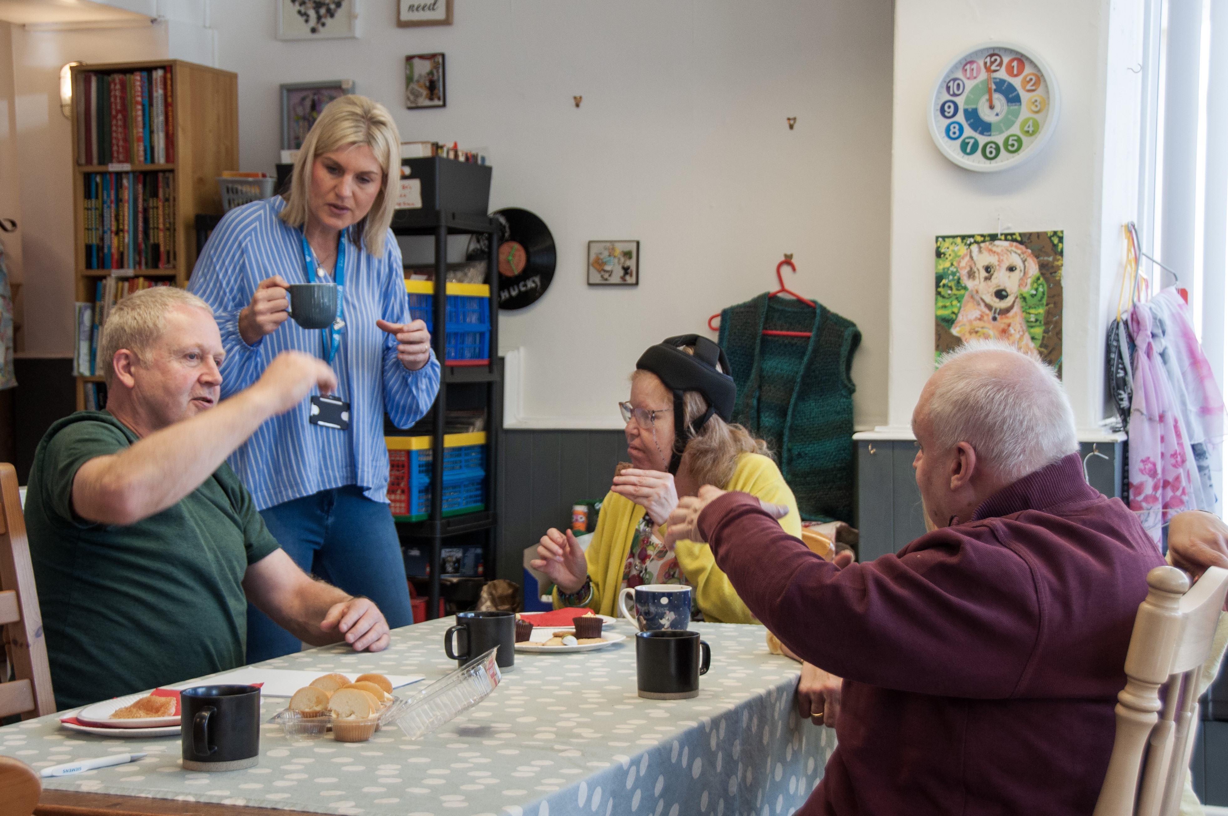 Shared Lives Coffee Morning, 3 People Sitting And One Standing Around A Table With Tea And Cakes